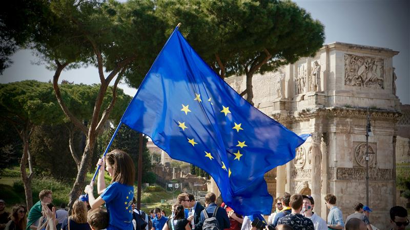 Young adult waving with an European Union flag - photo by Antoine Schibler Gimanu via Unsplash